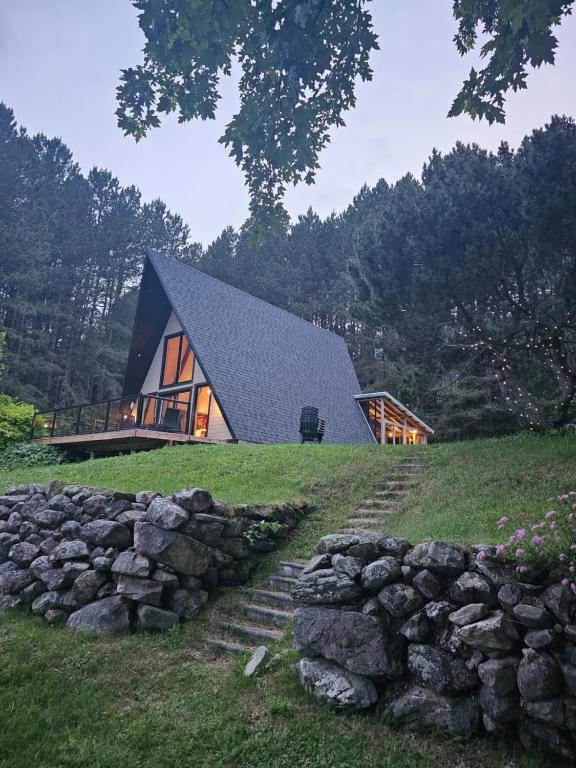 ein Haus mit einem schwarzen Dach und einer Steinmauer in der Unterkunft Chalet le Léandre in Cabano