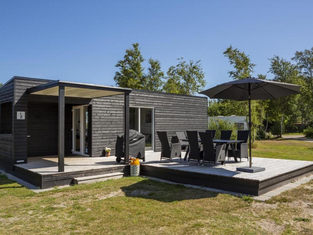 a small house with a patio and an umbrella at DCU-Camping Ålbæk Strand in Ålbæk