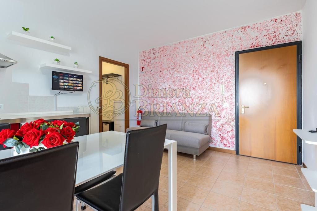 a dining room with a table with red roses on it at LT Dimora Brianza in Bovísio-Masciago Milanese