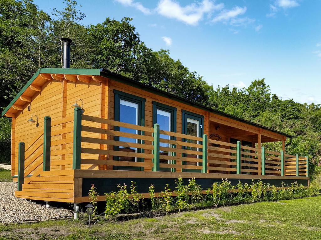 a wooden cabin with a large porch and windows at Dôl Werdd Lodge in Glanamman