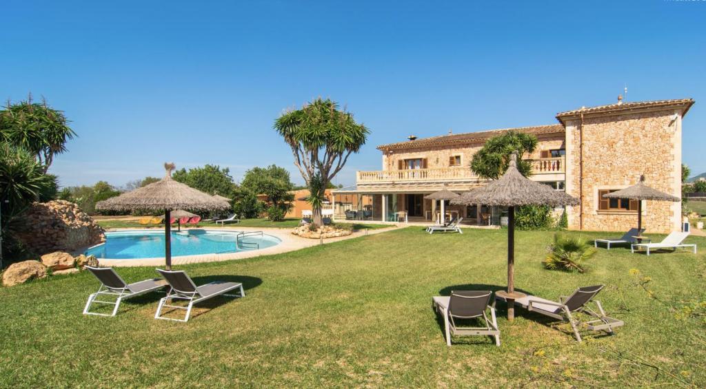 a yard with chairs and umbrellas and a pool at Finca Leilani in Llucmajor