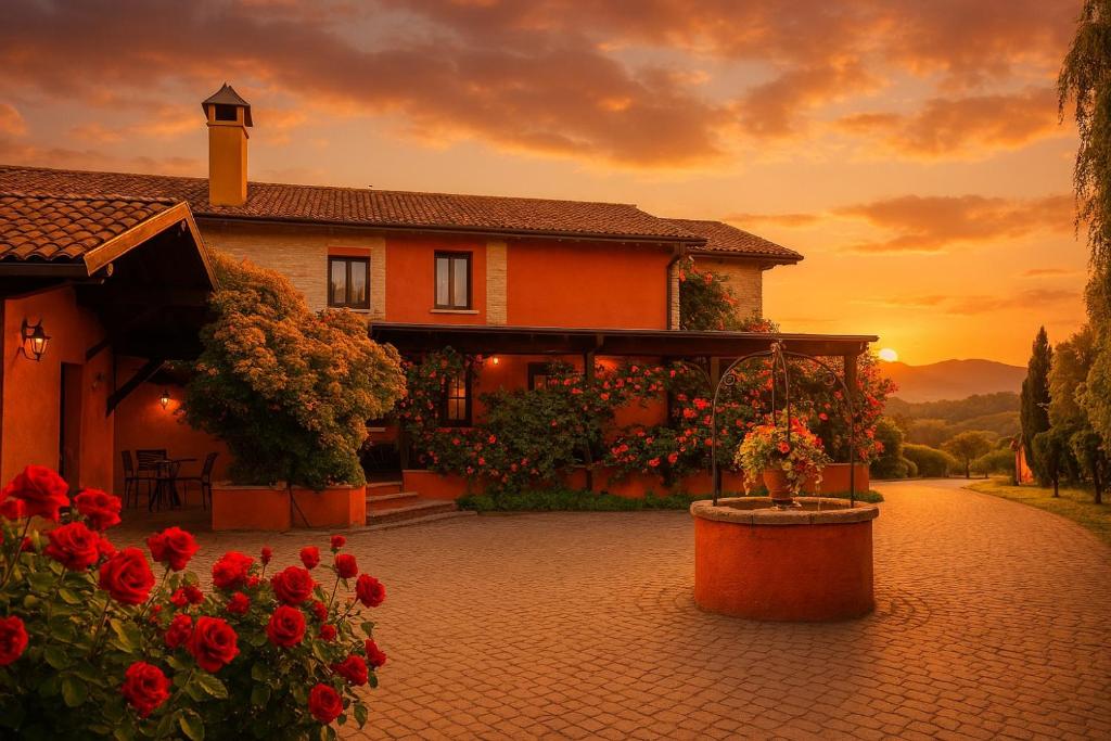 a house with red flowers and a sunset in the background at Relais Ca del rio in Botteghino di Zocca