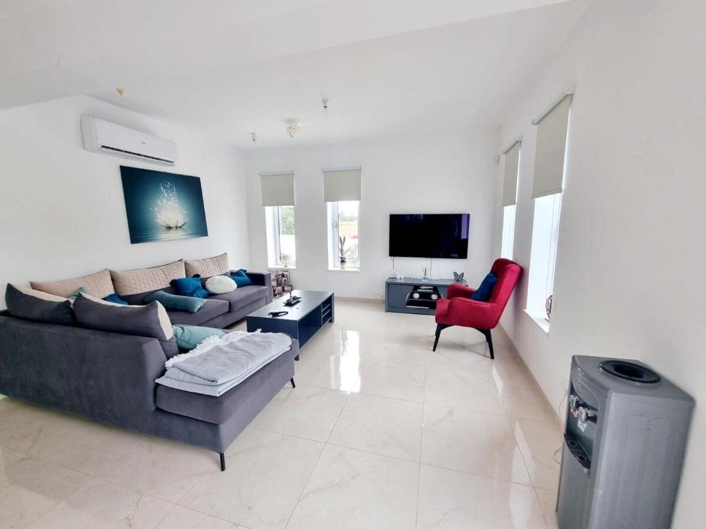 a living room with a couch and a red chair at luxury villa utopia 2 in Paphos