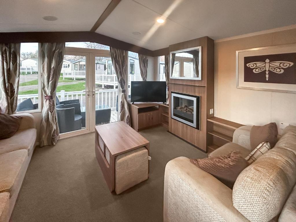 a living room with a couch and a tv at Simon's Coastal Holiday Home in Ormesby Saint Margaret