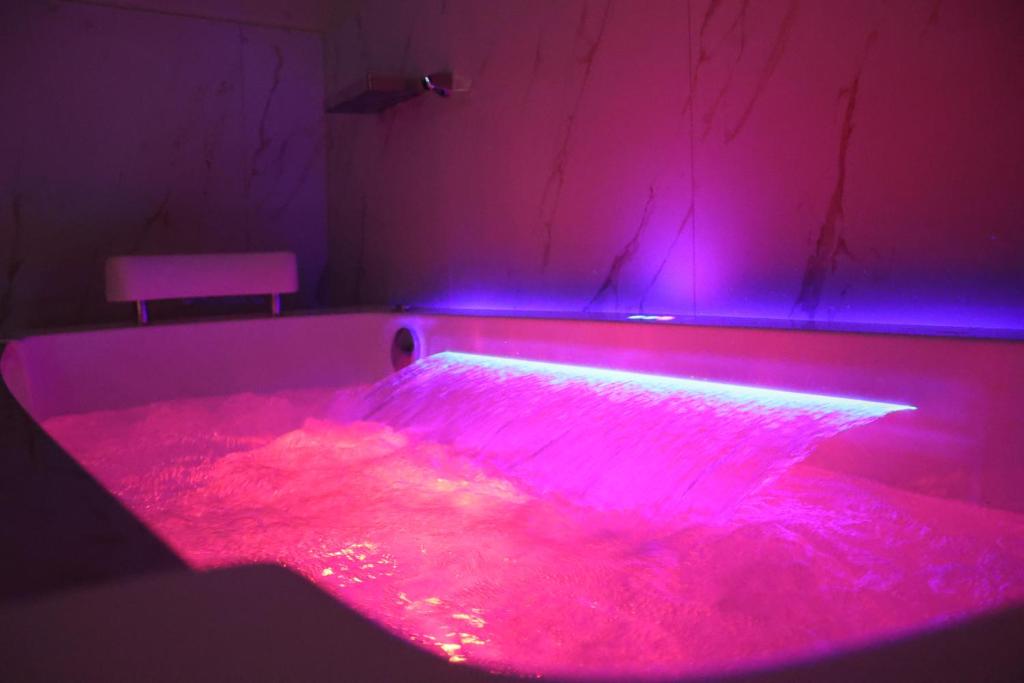a room with a tub with pink and blue lights at SSS Luxury Apartment with Jacuzzi in Kamëz
