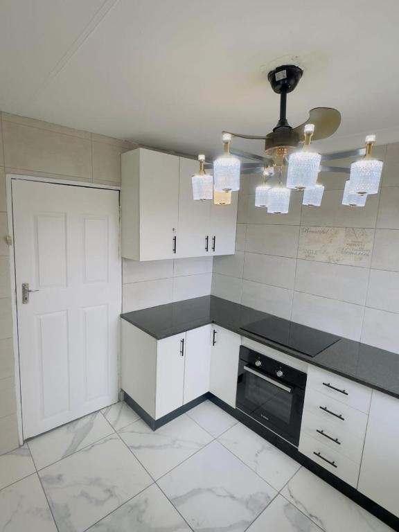 a kitchen with white cabinets and a black appliance at Le Maire Gust Lodge in Johannesburg