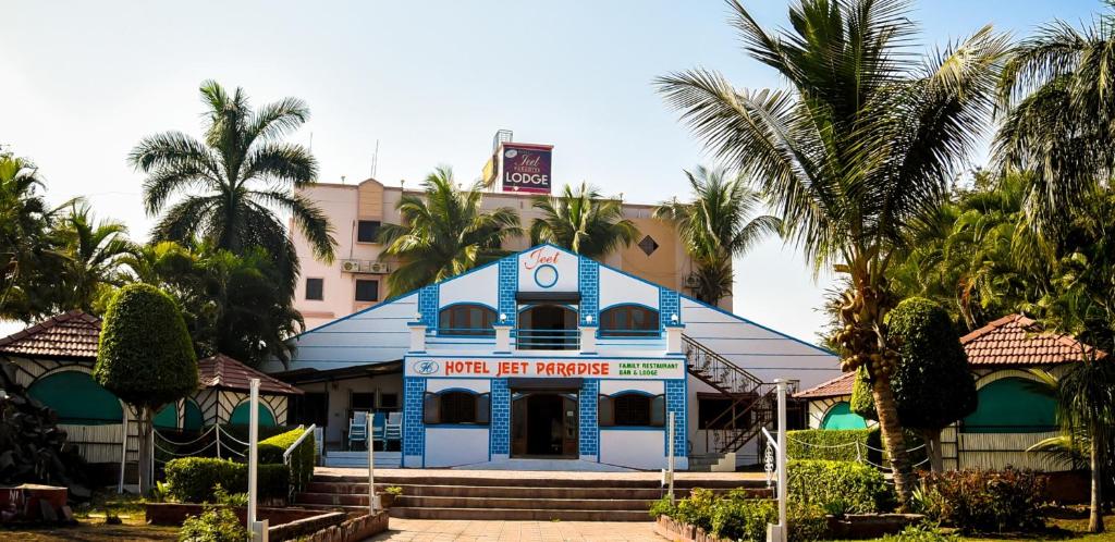 a blue building with palm trees in front of it at Hotel Jeet Paradise in Phaltan