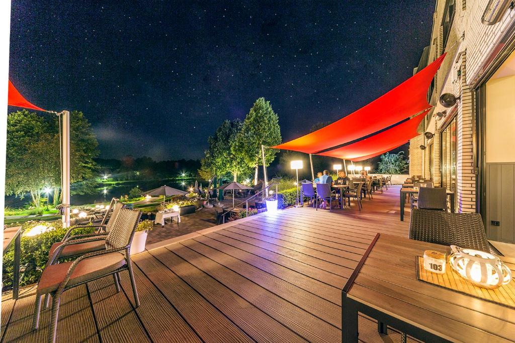 eine Holzterrasse mit Stühlen und Tischen in der Nacht in der Unterkunft See und Sporthotel Ankum Lakeside Apartments in Ankum