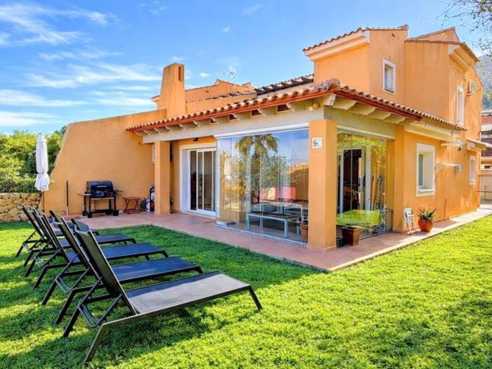 a house with a lawn with chairs in front of it at Casa Relax in Polop - Jacuzzi and Pool in Polop