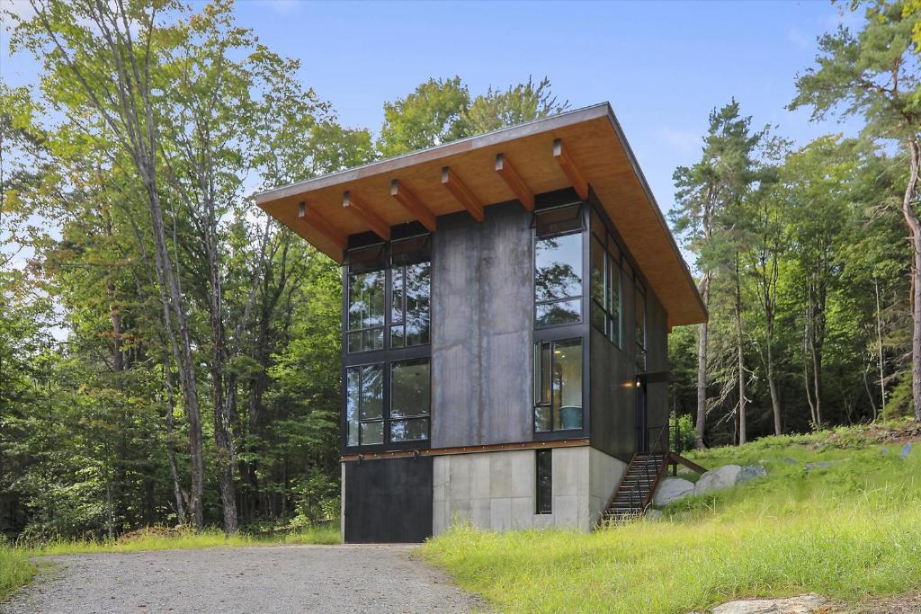 a small house with a wooden roof on a hill at Sterling Treehouse in Stowe Fork