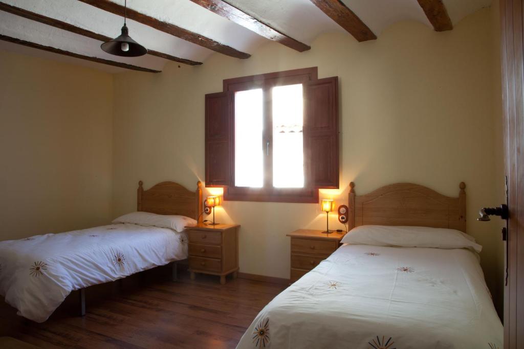 two beds in a room with a window and two lamps at Casa Abuelina in Titaguas