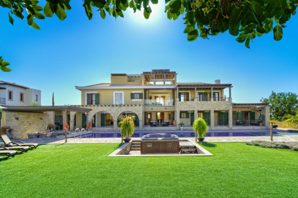 uma casa grande com um relvado em frente em 5 bedroom Villa Rio with large private pool and hot tub, Aphrodite Hills Resort em Kouklia