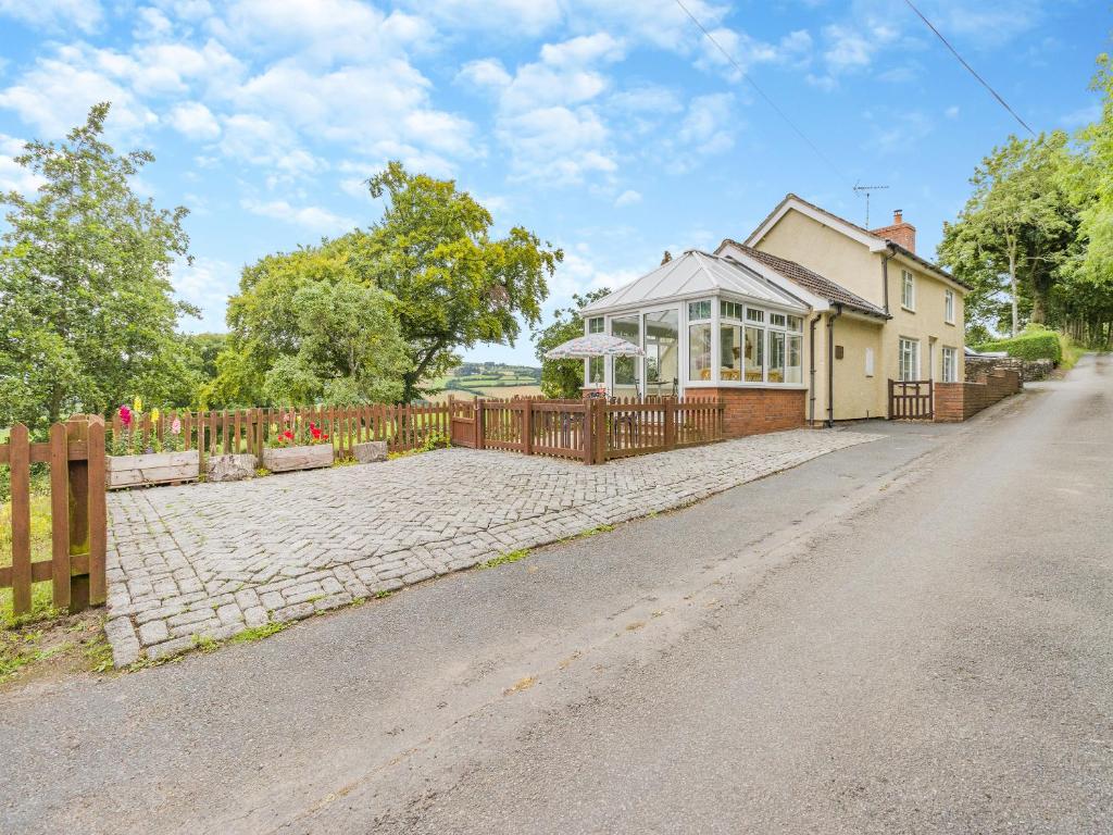 a house with a fence in front of a driveway at Mavis Cottage in Kington