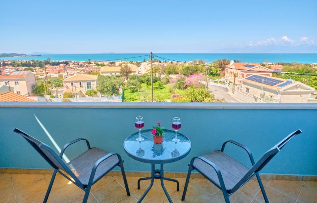 a table with two glasses of wine on a balcony at Casa Di Kontini in Acharavi
