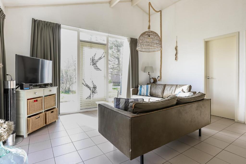 a living room with a couch and a tv at Rekerlande 274 in Warmenhuizen
