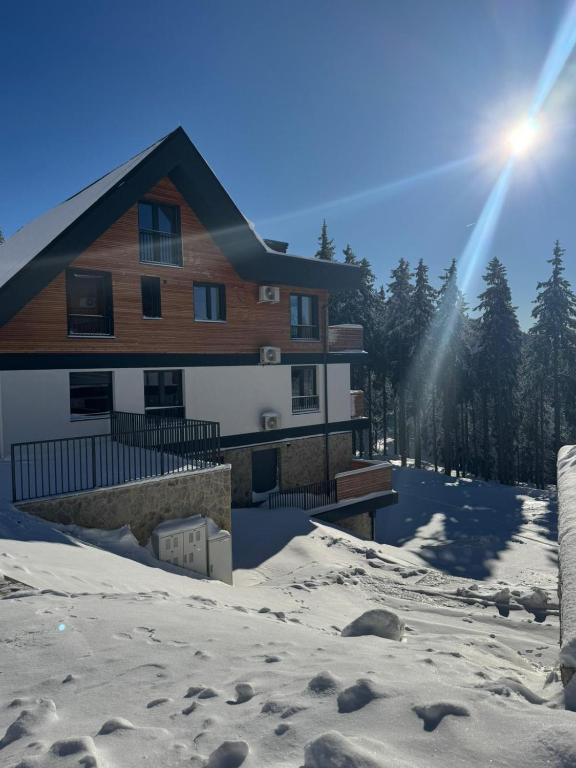 a house in the snow with the sun shining at Apartment Moné - Kope in Slovenj Gradec
