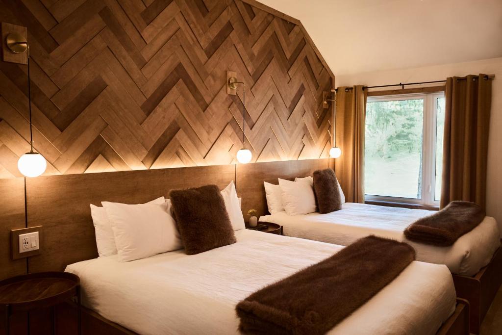 a hotel room with two beds and a window at Motel Boutique Hygge - anciennement Aux Portes du Soleil in Baie-Saint-Paul