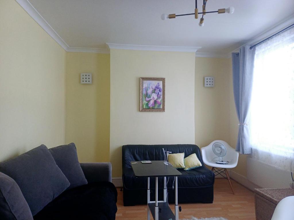 a living room with a couch and a table at Entire flat with 2 separate rooms in Norwood