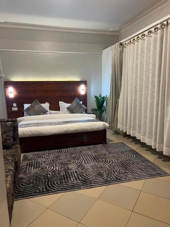 a bedroom with a large bed and a rug at Vine Gardens & Hotel, Mityana in Mityana