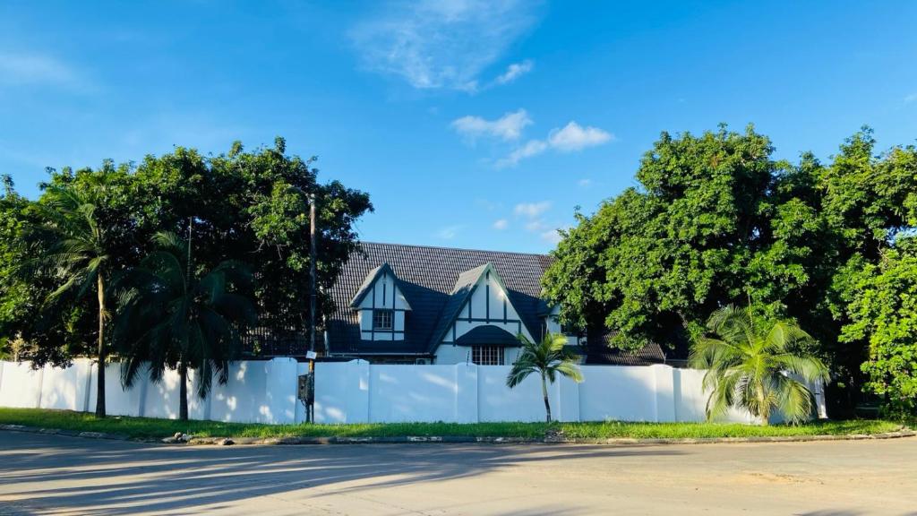 a house behind a white fence with palm trees at The Oasis Guesthouse in Mtubatuba