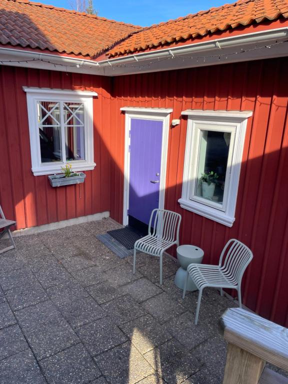 a red house with two chairs and a door at Guesthouse Holmen in Färgelanda