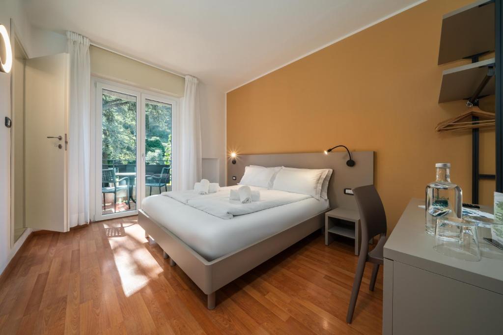 a bedroom with a bed and a desk and a window at Ventus Park Hotel in Nago-Torbole