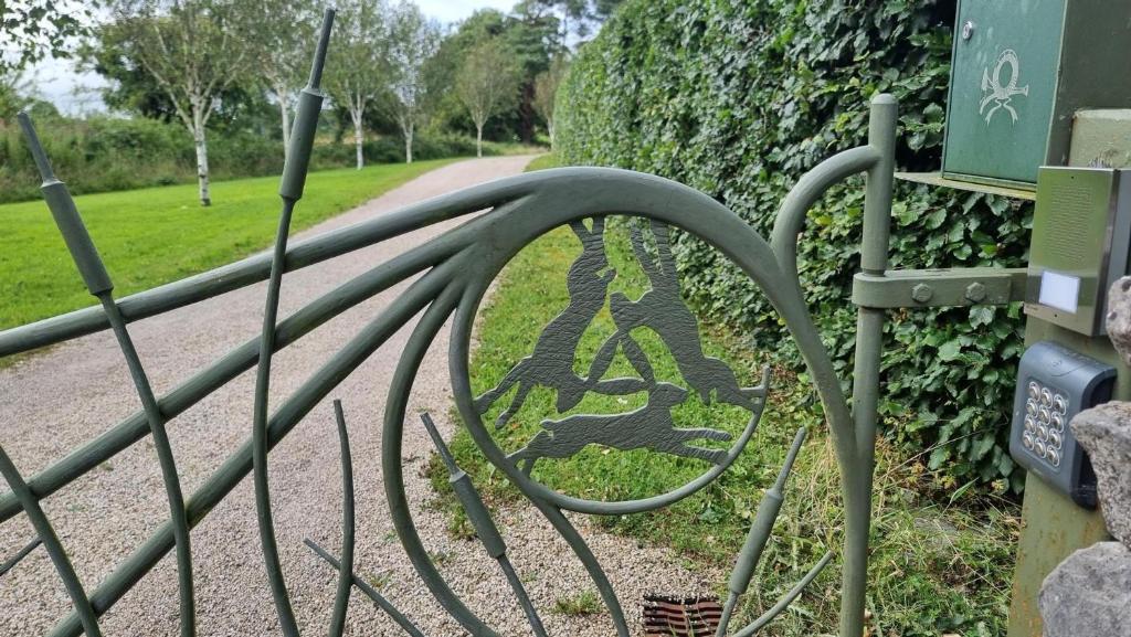 a metal gate with a sign on the side of a road at Three Hares Farmhouse, Galway in Craughwell