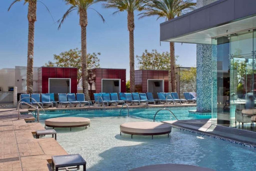 a swimming pool with lounge chairs and palm trees at Palms Place No Resort fees with Balcony in Las Vegas