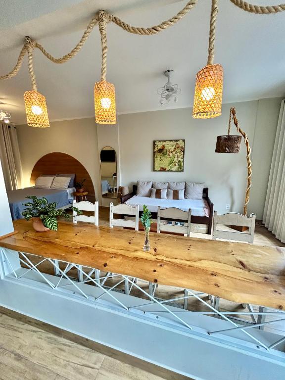 a living room with a bed and a wooden table at Apto estúdio na praça central in Serra Negra