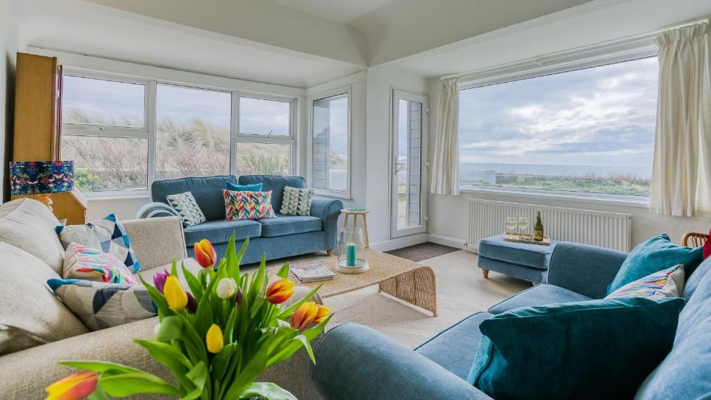 a living room with blue couches and windows at Borth Mawr in Rhosneigr