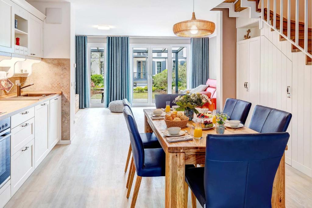 a kitchen and dining room with a wooden table and blue chairs at FeWo Am Pier 7a in Loddin