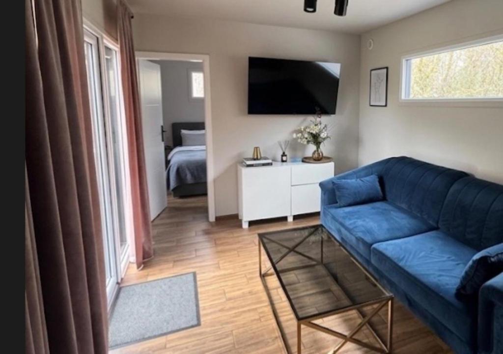 a living room with a blue couch and a bedroom at Domki La Bella 1 in Aleksandria