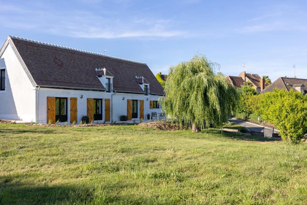 a white house with a tree in a field at Domaine des Chênes in Saint-Pierre-les-Étieux