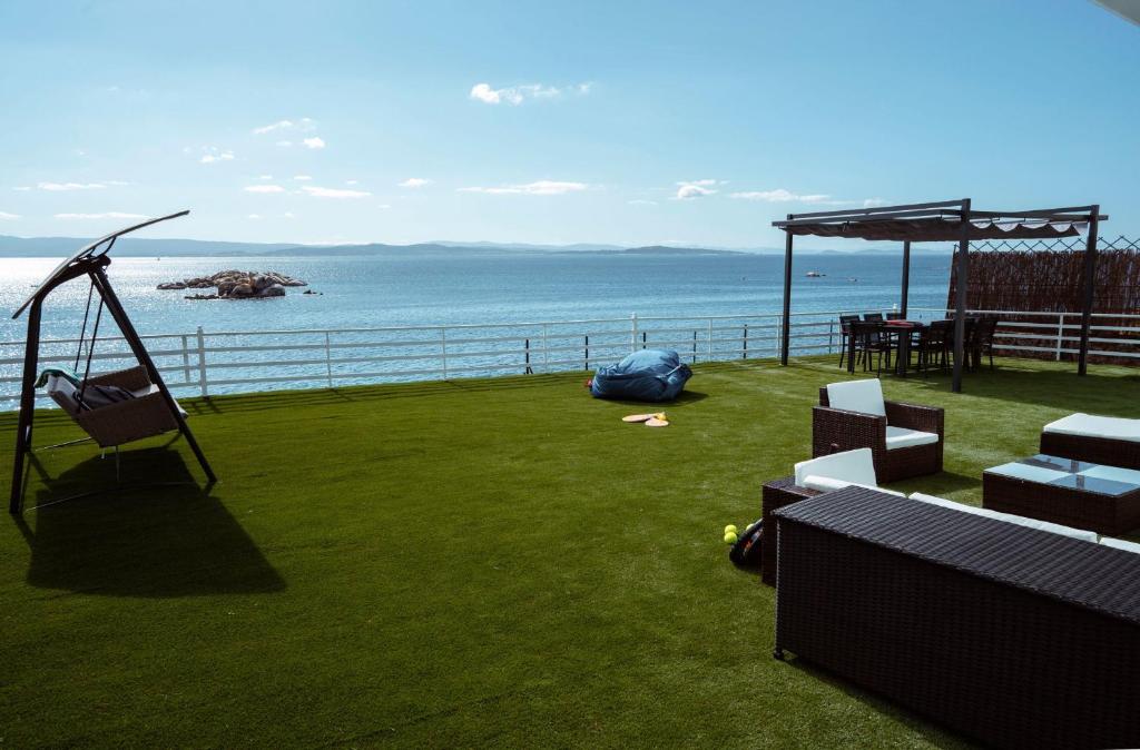 a playground with a swing and chairs and the ocean at La Marisol Ribeira in Ribeira