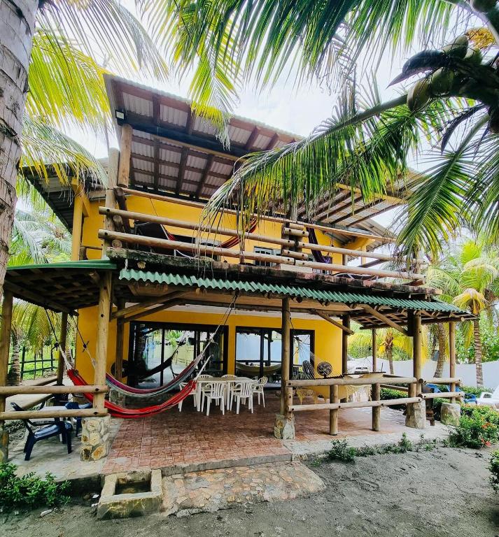a yellow building with a hammock and a table and chairs at Gaia - Casa de Playa in San Bernardo del Viento