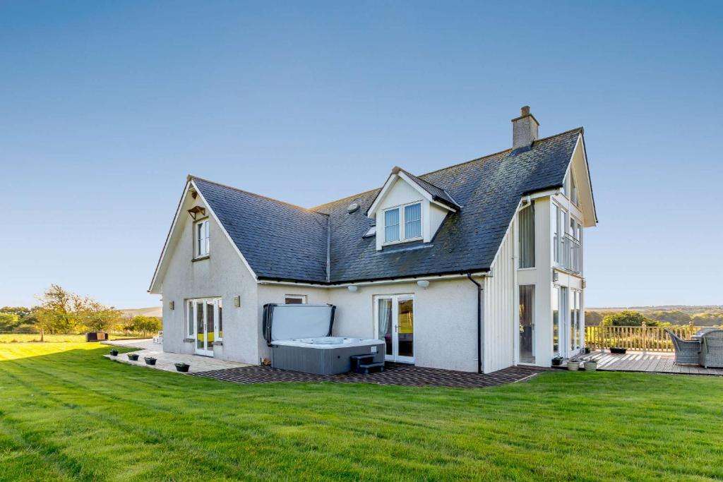 a white house with a large grass yard at Taigh Gleusta in Angus