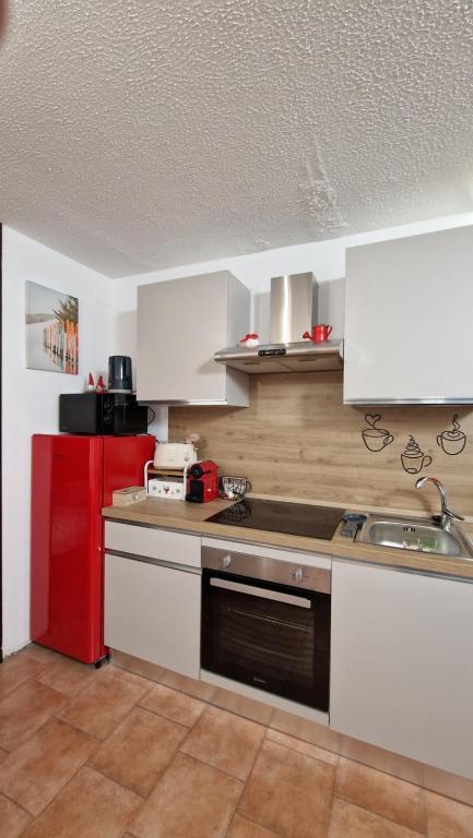 a kitchen with white cabinets and a red refrigerator at Il Cuore del Tonale in Passo del Tonale