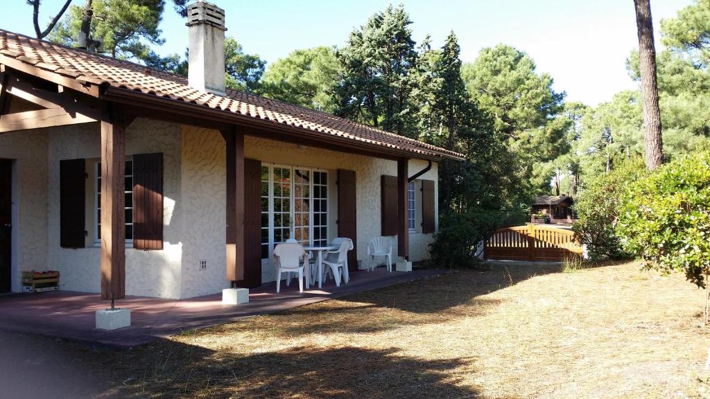 Casa con porche con mesa y sillas en Maison dans Quartier Calme en Lacanau-Océan