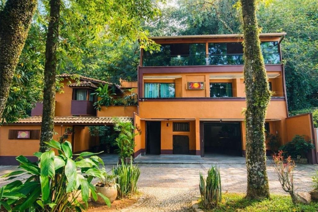 an orange house with trees in front of it at Pousada Sol e Cia Tur in Caraguatatuba