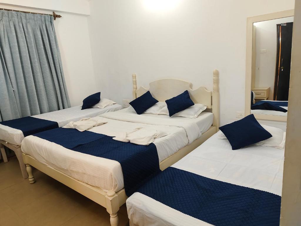three beds in a room with blue pillows on them at Leela Homes - Backpacker's Nest in Arpora