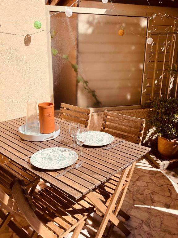 a wooden table with two plates and glasses on it at Le Val Claret in Antibes