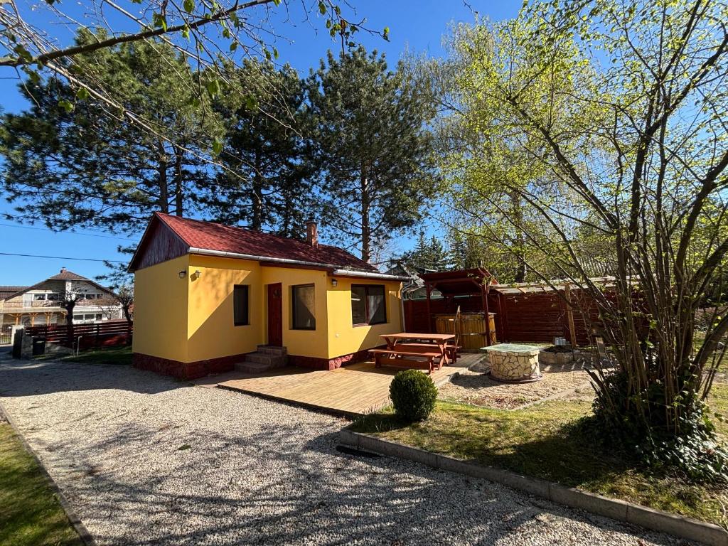 a small yellow house with a picnic table in a yard at Bambusz76 in Zamárdi