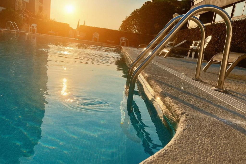a swimming pool with a metal handrail next to a pool at Apart CityMar 24h Terraza y vistas Ria Vigo in Vigo