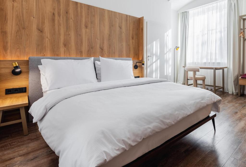 a bedroom with a large white bed with a wooden headboard at FortyPlusOne Hotel Vienna in Vienna