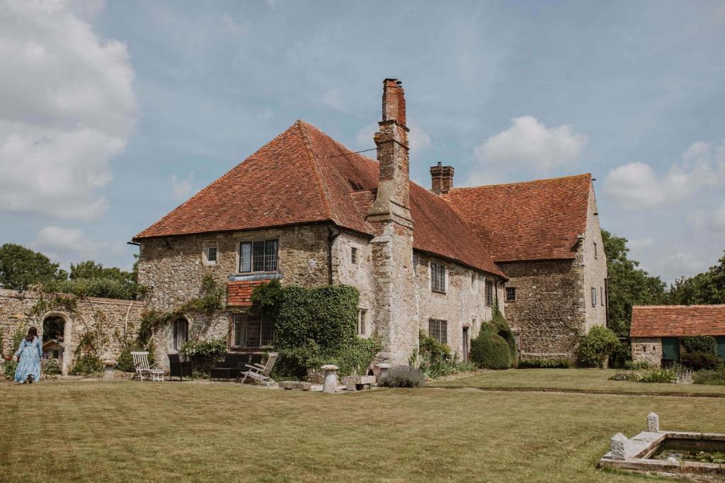 an old stone house with a chimney on a yard at The William Penn At Wickham Manor in Winchelsea