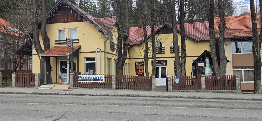 a yellow house with a fence in front of it at Pensiune Urban in Borsec
