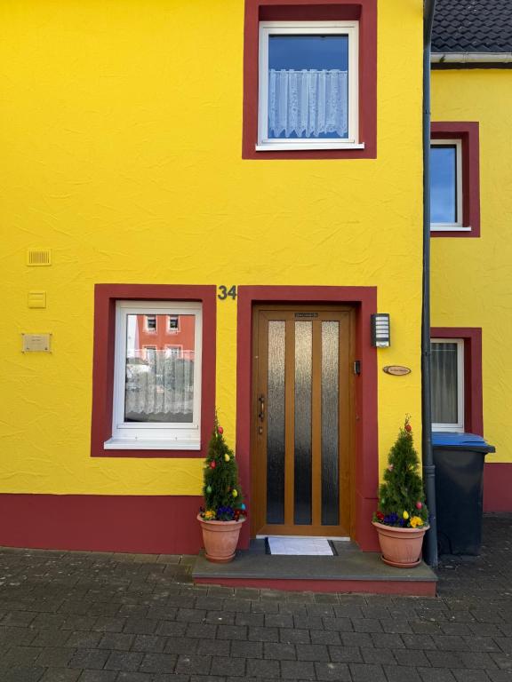 a yellow house with two potted plants in front of it at Das kleine Vulkanhaus in Daun
