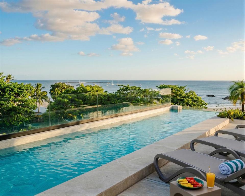 a swimming pool with a view of the ocean at Iguana Surf Boutique Hotel Tamarindo Rooftop Pool & Beachfront Suites in Tamarindo