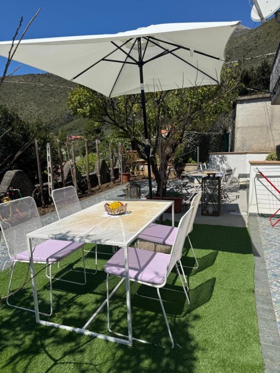 a table with purple chairs and a white umbrella at Nonna Maria B&B Home restaurant in La Marinella