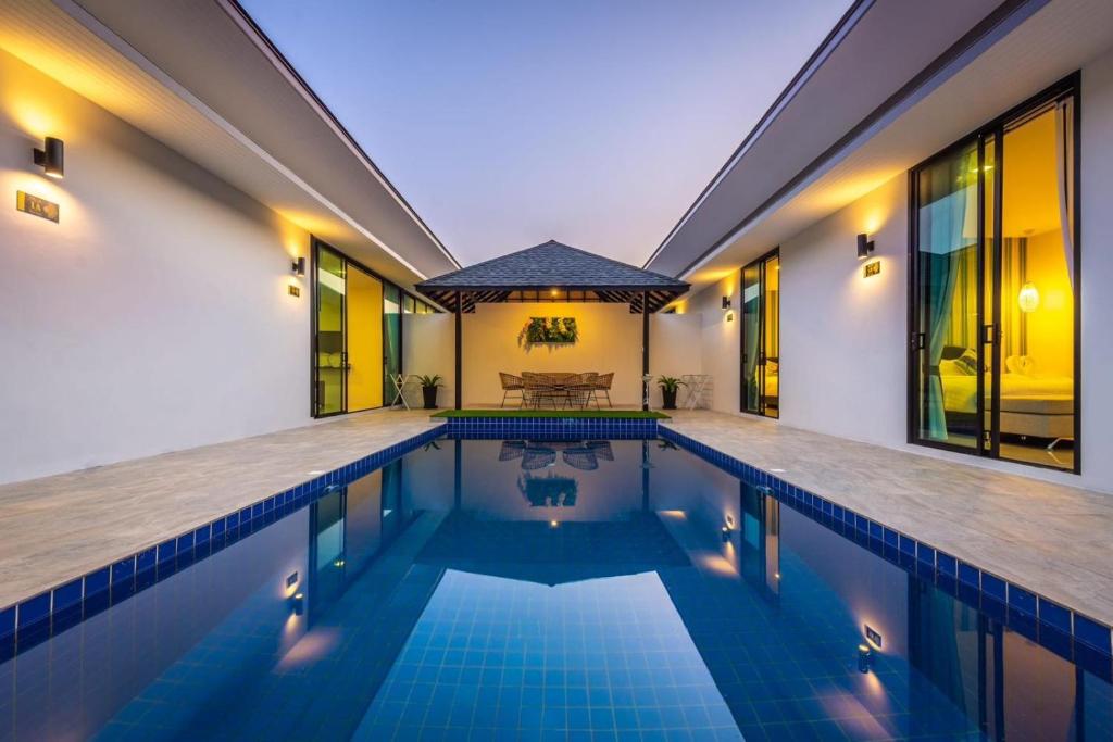 an indoor swimming pool with a house at Lespalm Resort by Vacayandco in Ban Thalat Choeng Thale